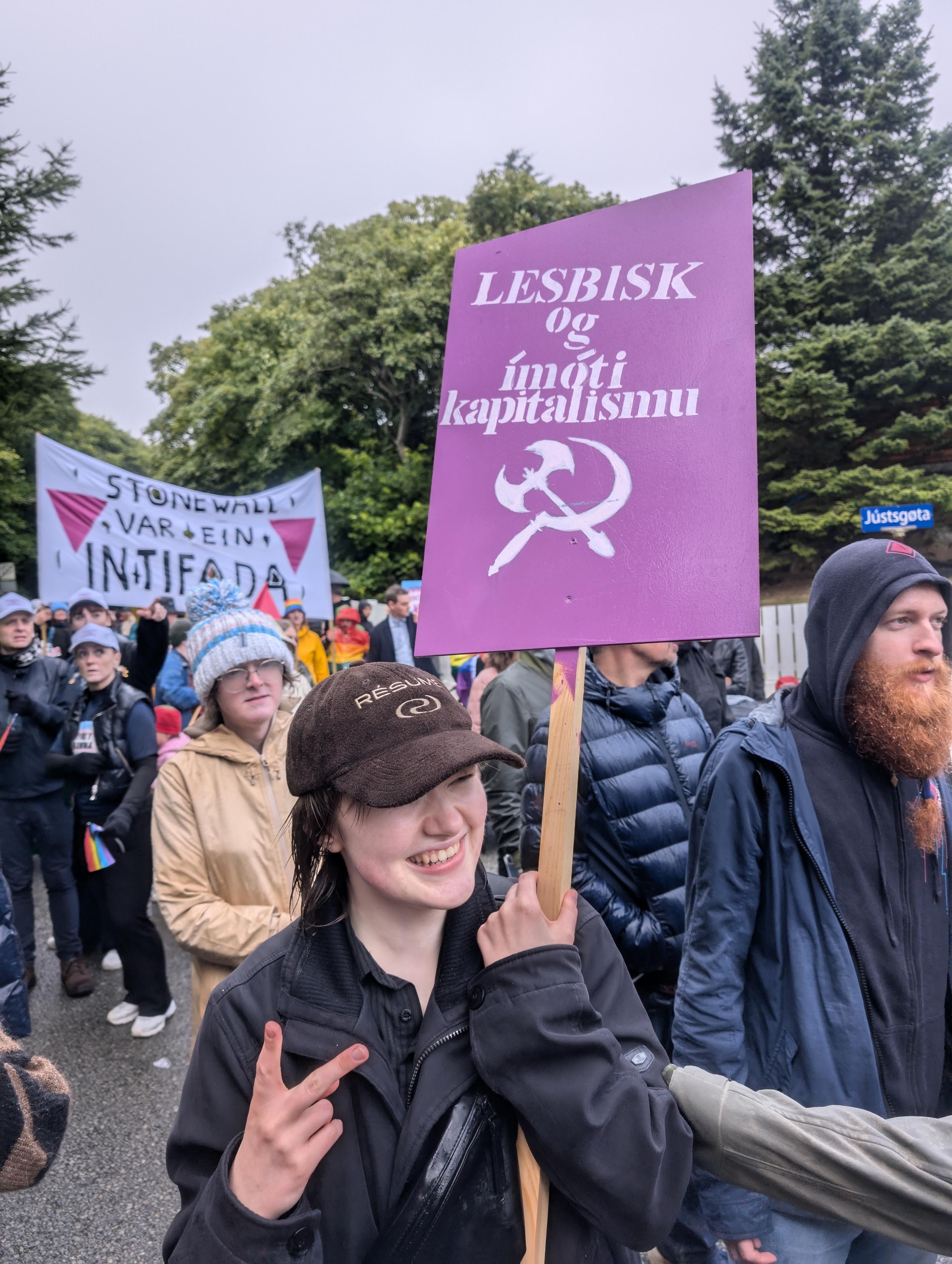 Ein í gonguni hevur eitt skeltið við tekstinum: 'Lesbisk og ímóti kapitalismu'. Skeltið hevur ein øks og ein sigd. Í bakgrundini er 'Stonewall var ein intifada' bannarin.